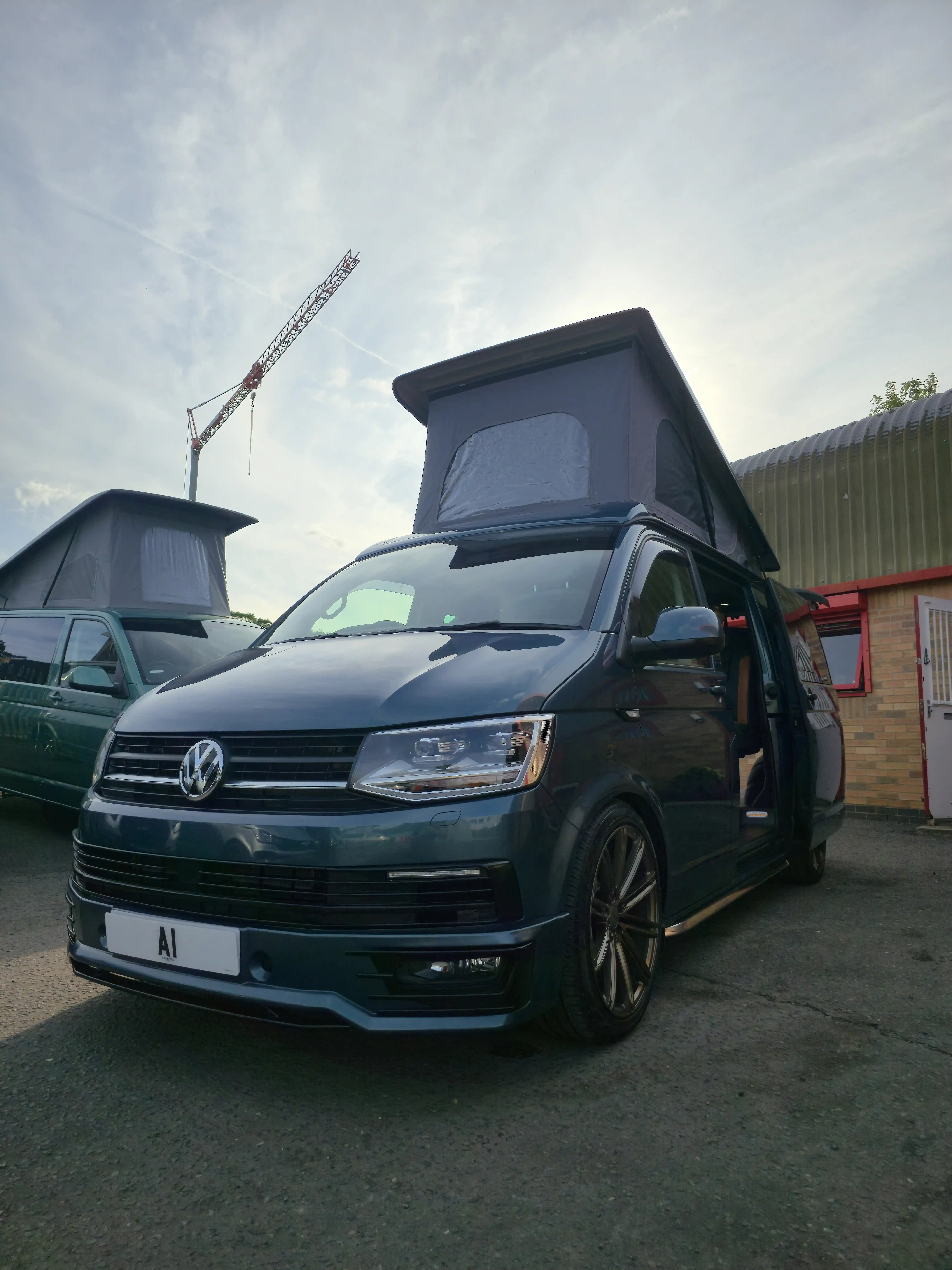 A gray volkswagen van that has been converted to campervan with custom detailing.